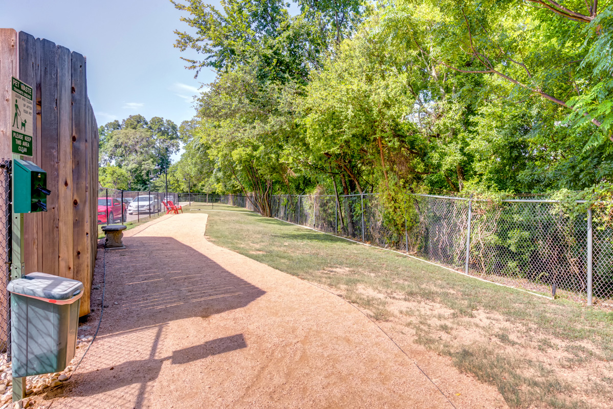 Fenced in dog park with walking trail, and bench-style seating